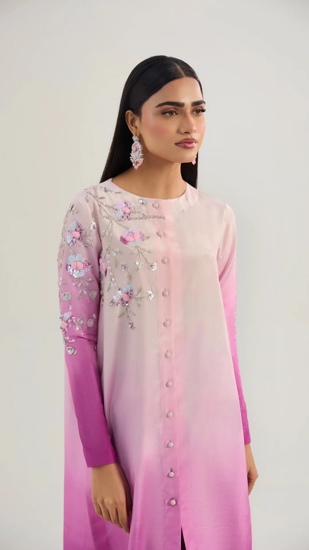 Woman wearing a pink and purple embroidered dress against a white background