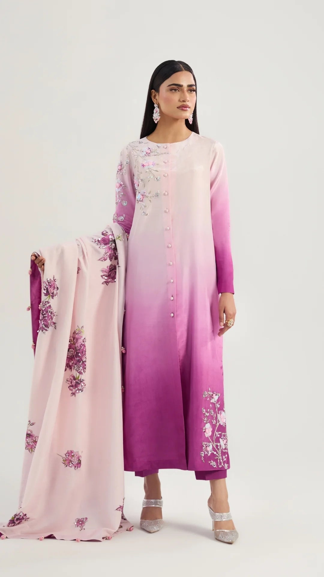 Woman wearing a pink and purple gradient outfit with floral patterns on a white background