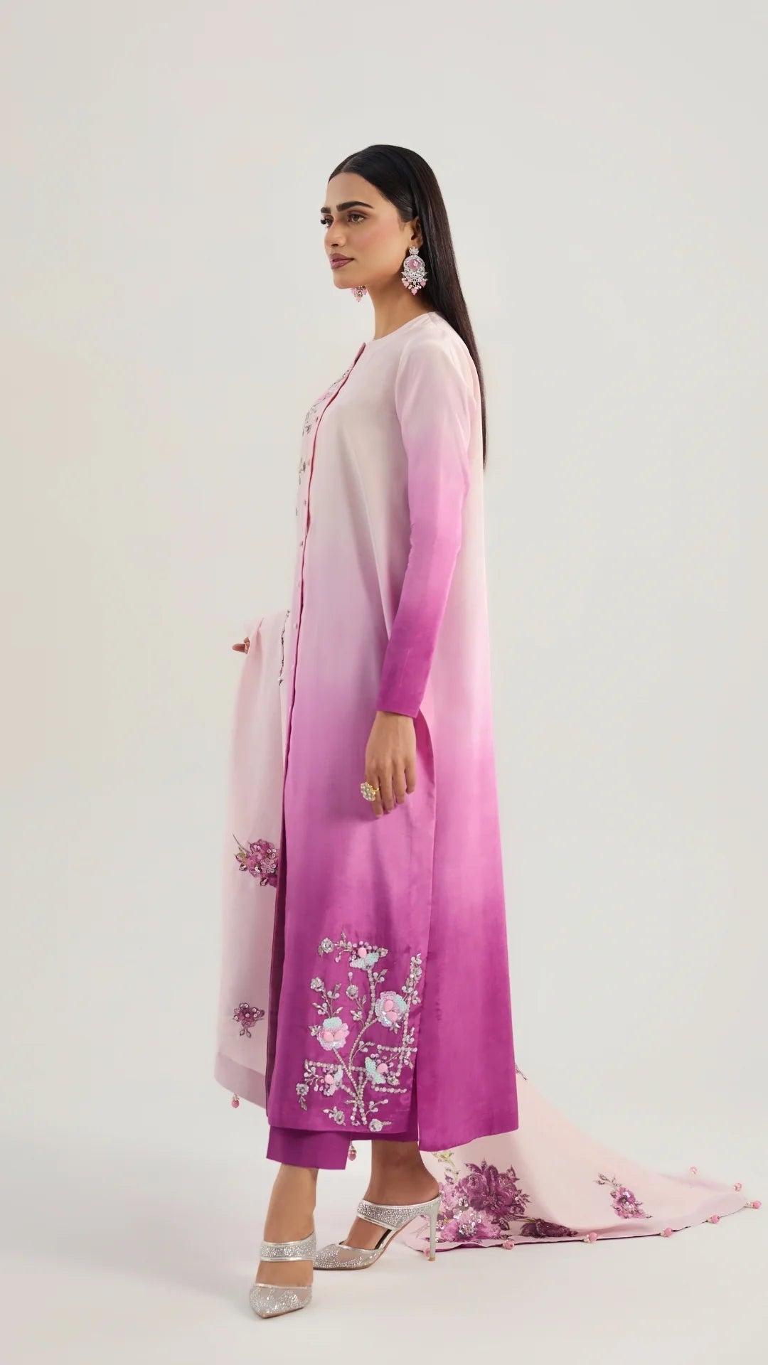 Woman wearing a pink and purple embroidered outfit on a white background