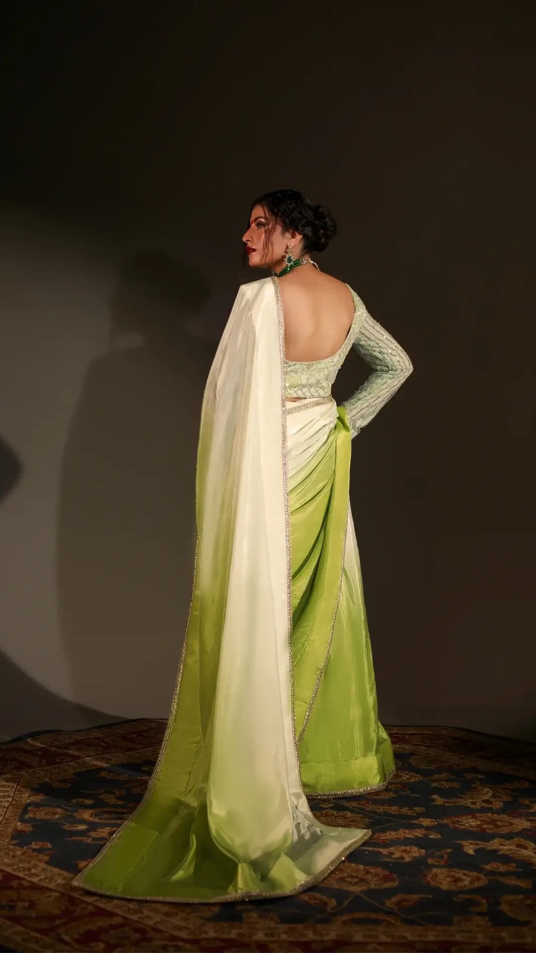 Woman wearing a green and white saree with a dark background