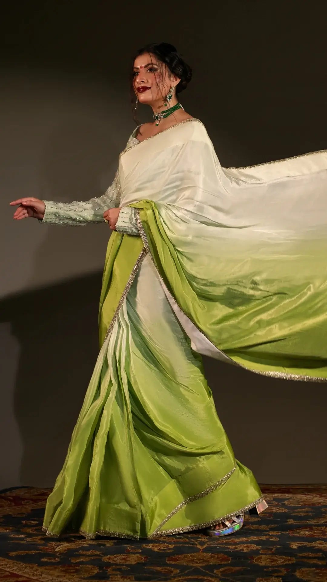 Woman in a green and white saree with a plain background