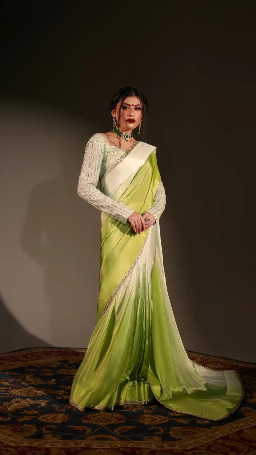 Woman wearing a green and white saree with a dark background