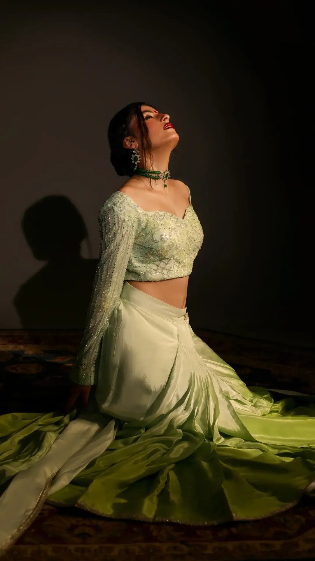 Woman in a light green traditional outfit against a dark background