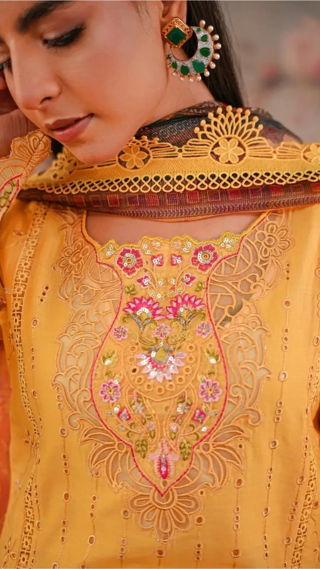 Close-up of a person wearing a yellow embroidered traditional outfit with intricate designs.