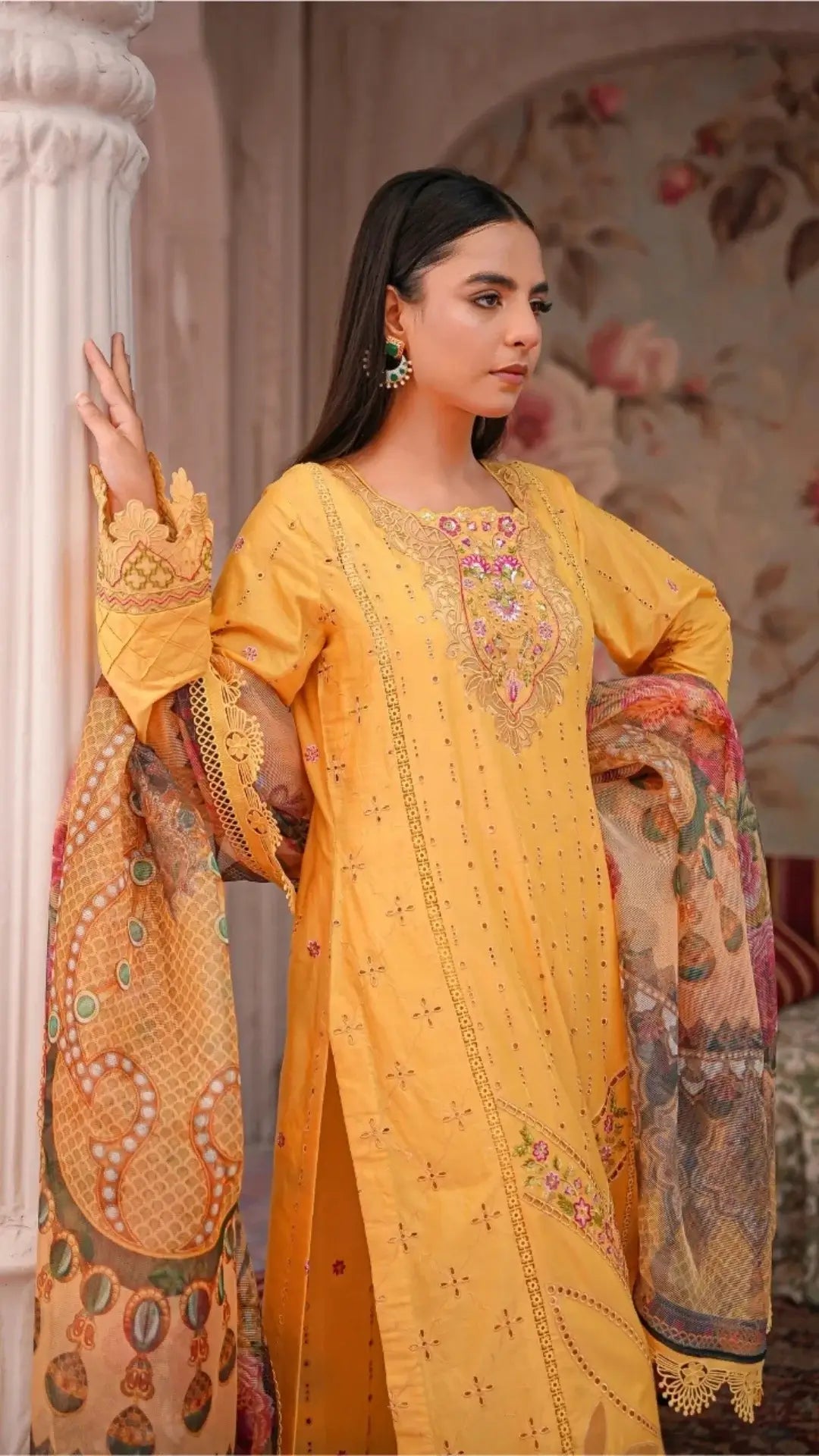 Woman wearing a yellow embroidered traditional outfit with a floral background