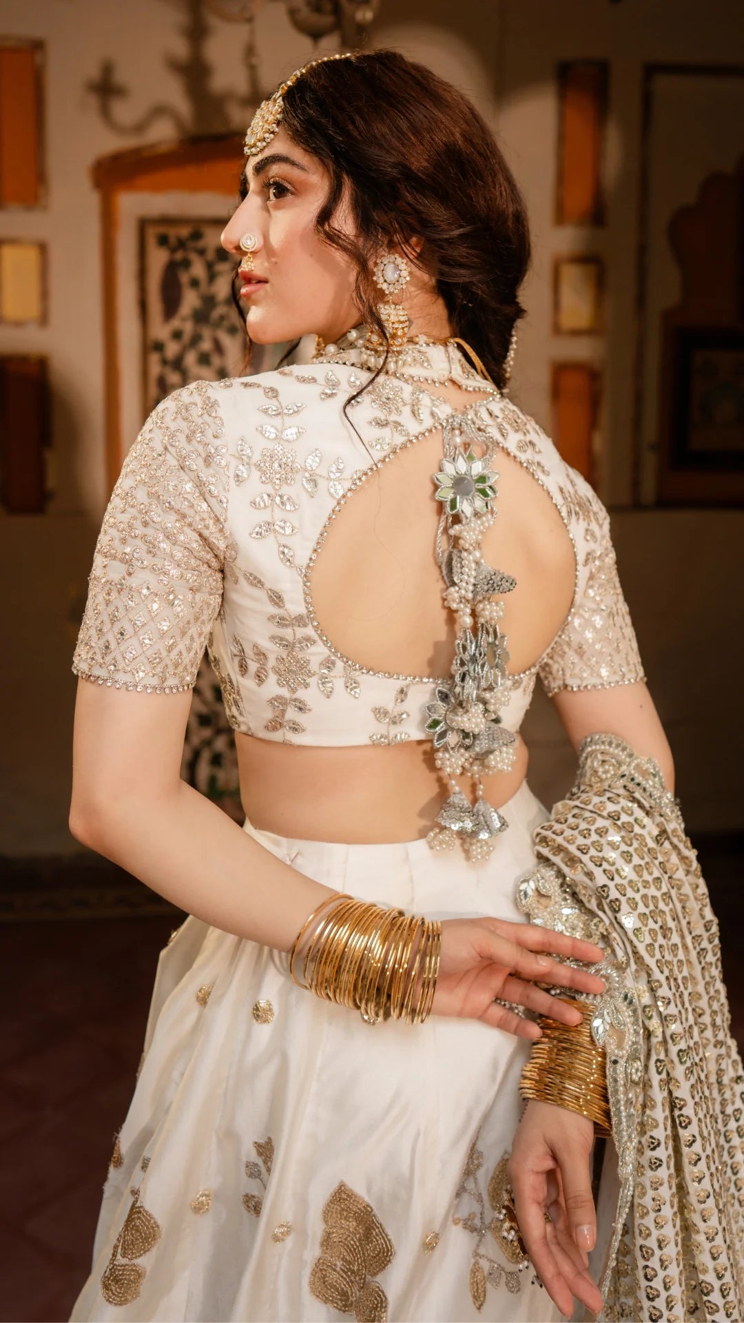 Woman in traditional attire with intricate jewelry and a floral blouse.
